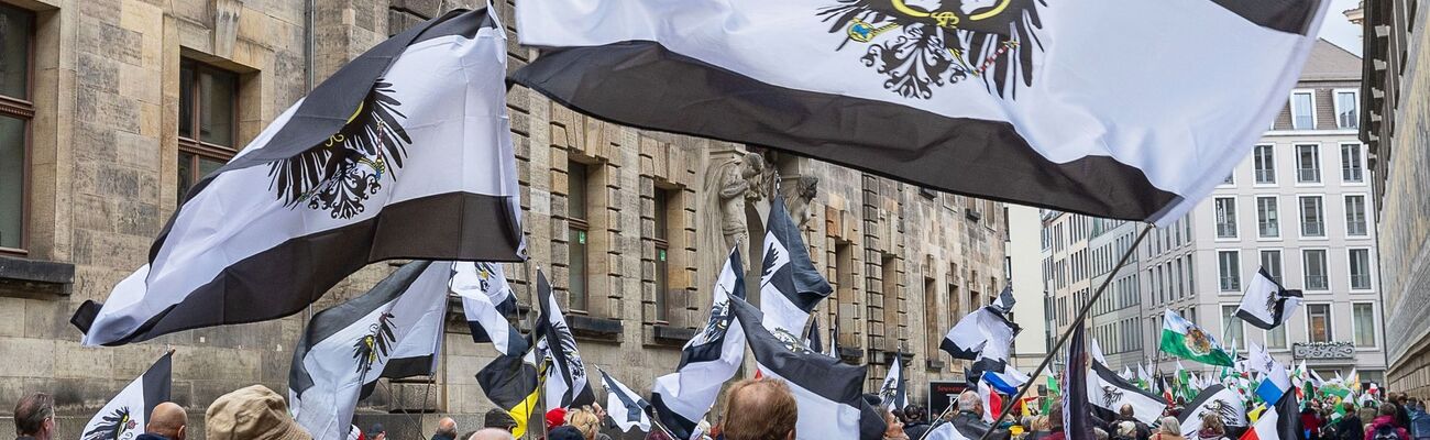 Mehrere hundert Teilnehmer einer Demonstration ziehen mit Flaggen vom Königreich Preußen (schwarz-weiß-schwarz mit Adler) durch die Innenstadt., © Daniel Schäfer/dpa-Zentralbild/dpa