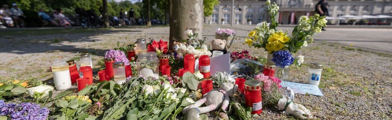 Blumen, Kerzen und handgeschriebene Trauerbekundungen stehen an einem Baum im Kurpark Bad Oeynhausen., © Str/dpa