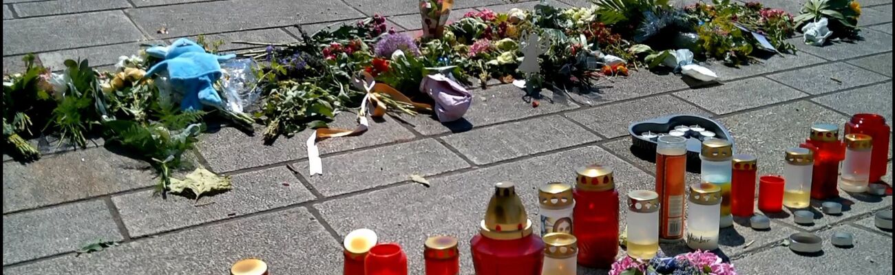 Blumen liegen und Kezen stehen auf dem Pflaster, während Menschen nach einem tödlichen Angriff im Kurpark trauern. ., © Sandra Knauthe/TNN/dpa