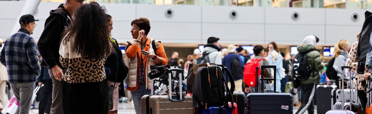 Am Flughafen in Düsseldorf stehen Reisende am Samstagmorgen mit ihren Koffern im Abflug-Terminal., © Christoph Reichwein/dpa