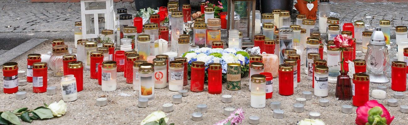 Trauerkerzen stehen an einem Tatort in der Paderborner Innenstadt neben Blumen. Vor dem Kiosk ist in der Nacht auf den 1. Mai ein 30-Jähriger ums Leben gekommen., © Friso Gentsch/dpa