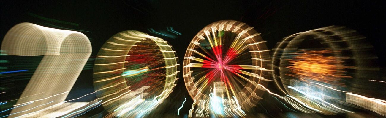 25 Jahre alt ist dieses «2000»-Foto: Ein Zoom-Effekt verfremdet eine große «2» und drei Riesenräder am Mainufer in Frankfurt in der Silvesternacht 1999/2000. , © Arne Dedert/dpa