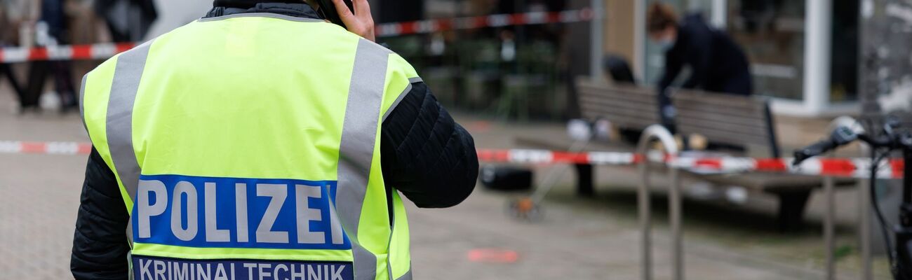 Eine Polizeibeamtin der Kriminaltechnik steht an einem abgesperrten Tatort in der Bielefelder Innenstadt. Ende Januar startet der Prozess nach dem Tod eines ehemaligen Boxers. (Archivbild), © Friso Gentsch/dpa