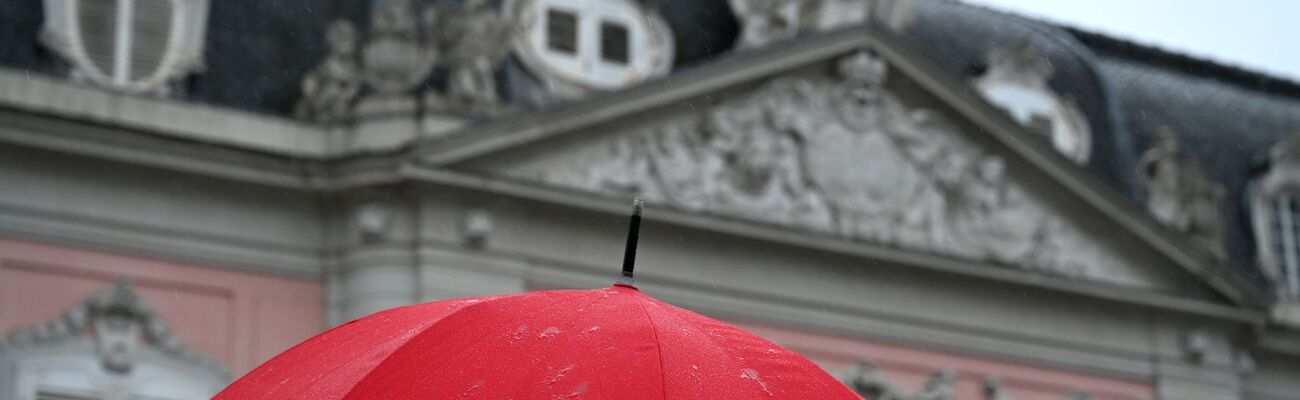 Eine Frau geht mit ihrem Regenschirm bei Regen am Schloss Benrath vorbei., © Wolf von Dewitz/dpa