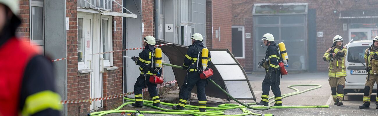 Feuerwehrleute bringen einen Brand in einer Lagerhalle in Köln unter Kontrolle., © Thomas Banneyer/dpa