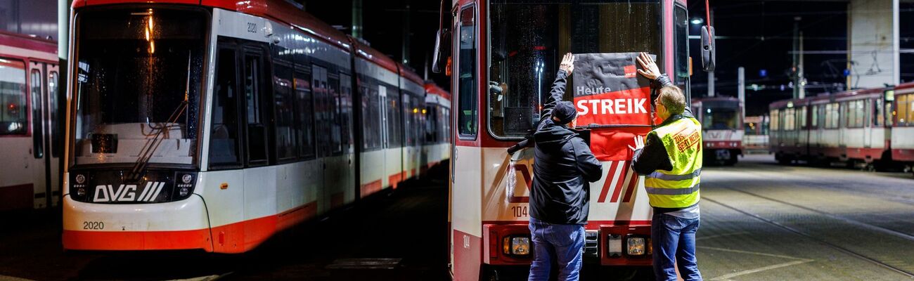 «Heute Streik» steht auf dem Plakat, dass Beschäftigte in Duisburg am frühen Morgen an eine Straßenbahn hängen., © Christoph Reichwein/dpa