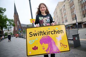 Die Stadt Gelsenkirchen wird im Juli Schauplatz für die «Eras Tour» von Superstar Taylor Swift - und gibt zu Ehren der Musikerin einen neuen Namen. Enthüllt wurde das «Swiftkirchen» von Swift-Fan Aleshanee Westhoff., © Bernd Thissen/dpa