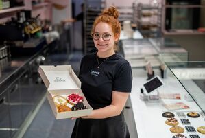 Eine Box mit frisch gebackenen und belegten Cookies präsentiert Mitgründerin Julia Boes., © Christoph Schmidt/dpa