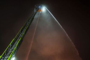 Von einer Drehleiter versucht die Feuerwehr, den Brand einer Lagerhalle zu löschen., © Christoph Reichwein/dpa