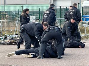 Polizisten halten Demonstranten am Boden fest. Sie hatten zuvor versucht mit Fahrrädern Richtung Veranstaltungshalle vorzudringen., © Jörg Ratzsch/dpa